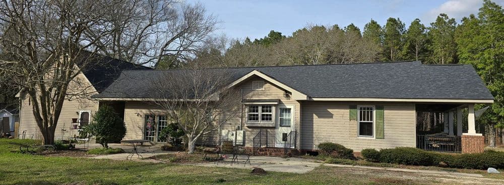 Modern one-story home with a new roof, surrounded by green trees and landscaped yard.
