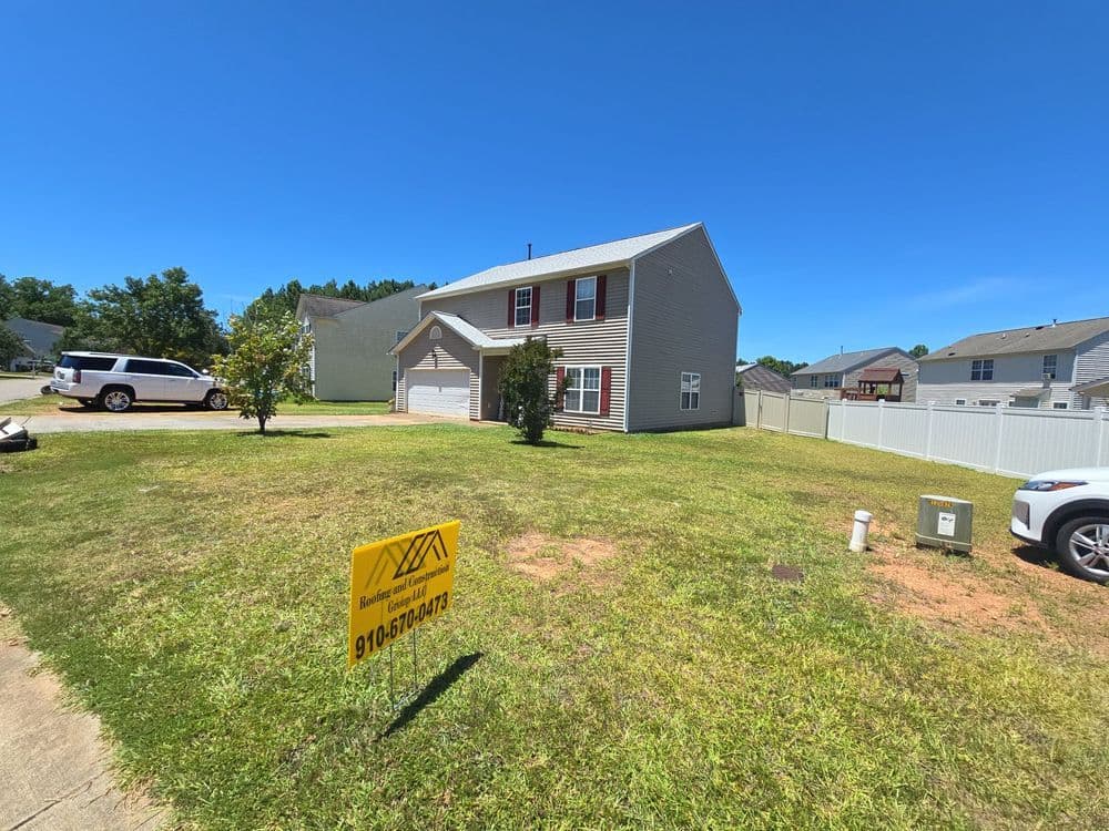 Two-story house with a yard and for sale sign, sunny day in residential neighborhood.