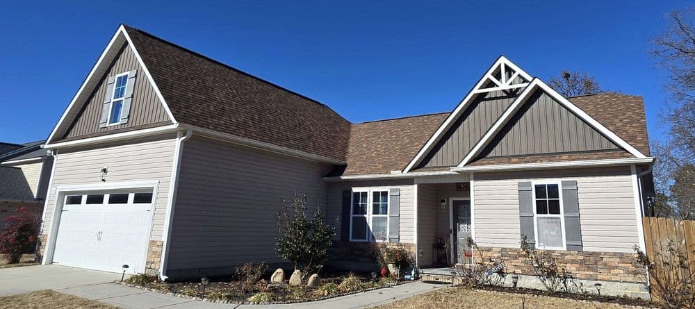 Modern suburban home with a gable roof, stone accents, and landscaped front yard.