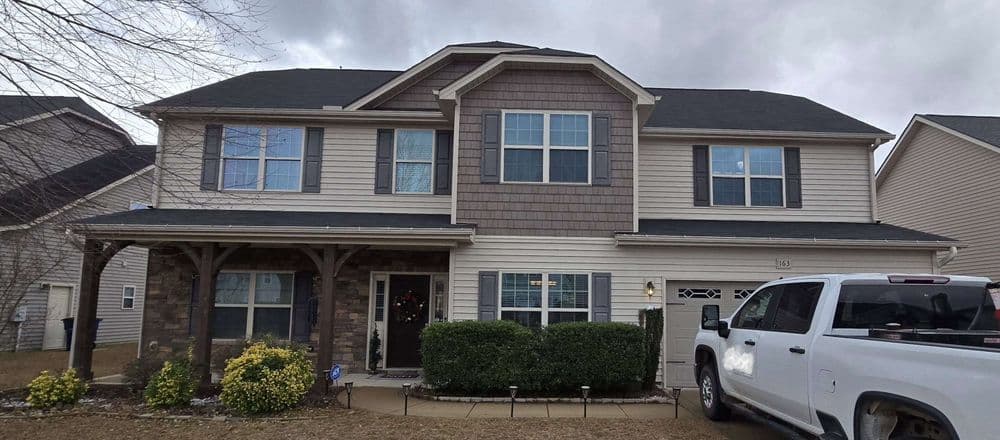 Two-story suburban home with stone accents, large windows, and landscaped front yard.