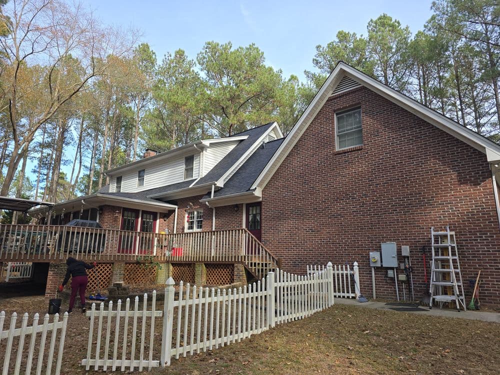 Residential backyard with a wooden deck, fence, and home renovations underway.
