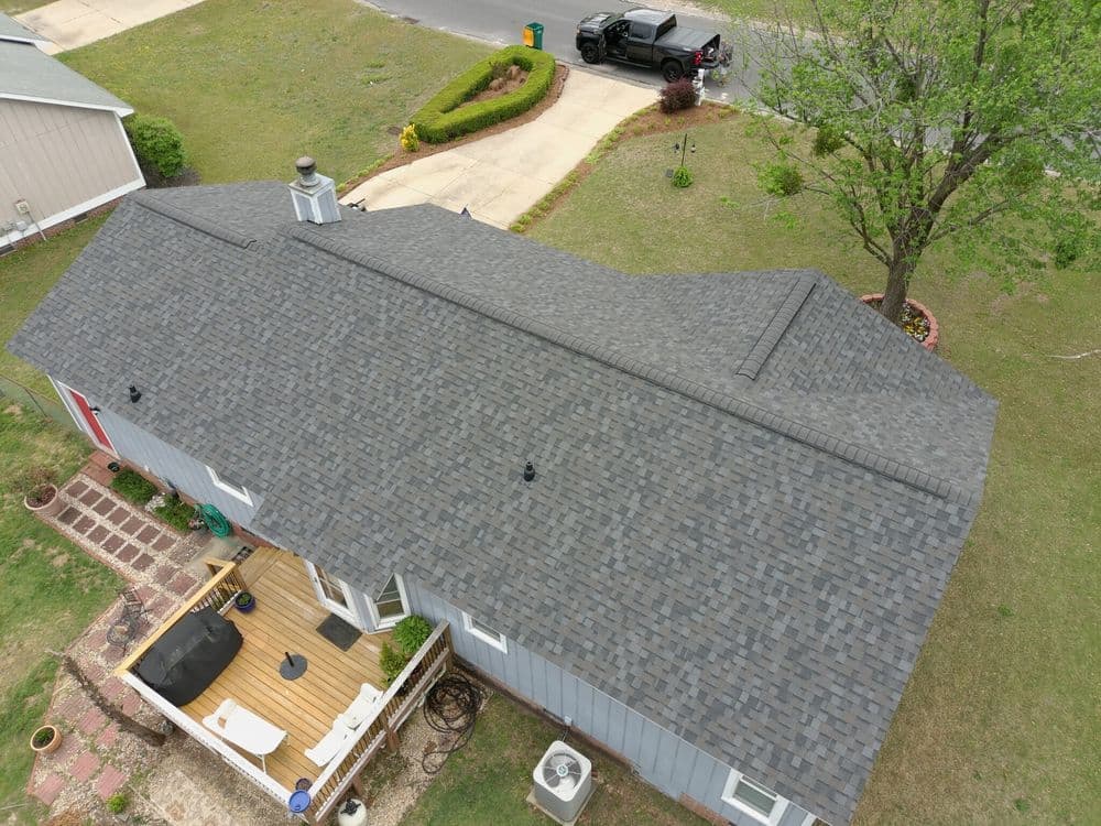 Aerial view of a modern home with a gray roof, deck, and landscaped yard.