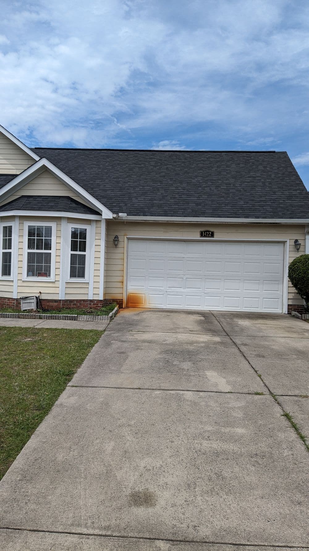 Front view of a residential home with a garage and driveway under a blue sky.